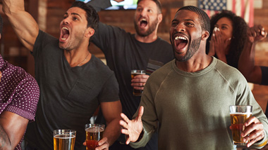 group of fans excitedly watching game on tv in a bar