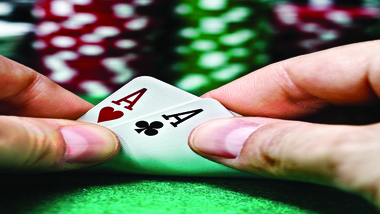 Pocket aces on a green felt poker table with poker chips in the background
