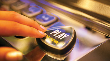fingers pressing play button on slot machine