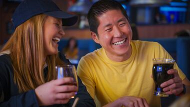 A man and woman having drinks at the Sportsbook Restaurant.