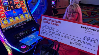 A woman holding a big check for $13,066.54