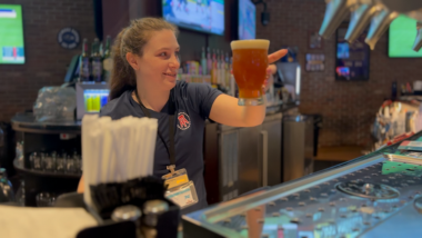 A bartender at Barstool Sportsbook Restaurant pouring a beer on tap. 