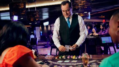 A picture of a craps dealer in action. 