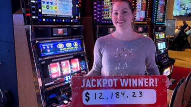 Woman smiling and holding a sign that says she won a $12,184 jackpot!