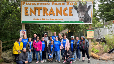 A group of Hollywood Team Members wear Hollywood Cares shirts standing at the entrance to Plumpton Park Zoo