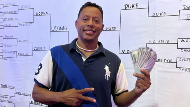 Winning Guest posing in front of the Bracket Challenge Banner.
