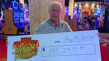 Guest holding up a giant check with their $188,257 jackpot written on it