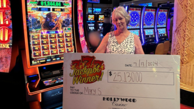 Guest holding up a giant check with their $25,130 jackpot written on it