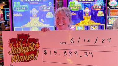 Woman smiling at holding up a large check with her jackpot written on it