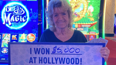 Guest holding up a sign that says "I won $5,000 at Hollywood!"